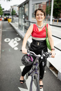 Tamar Shapiro on bicycle with bus stop nearby