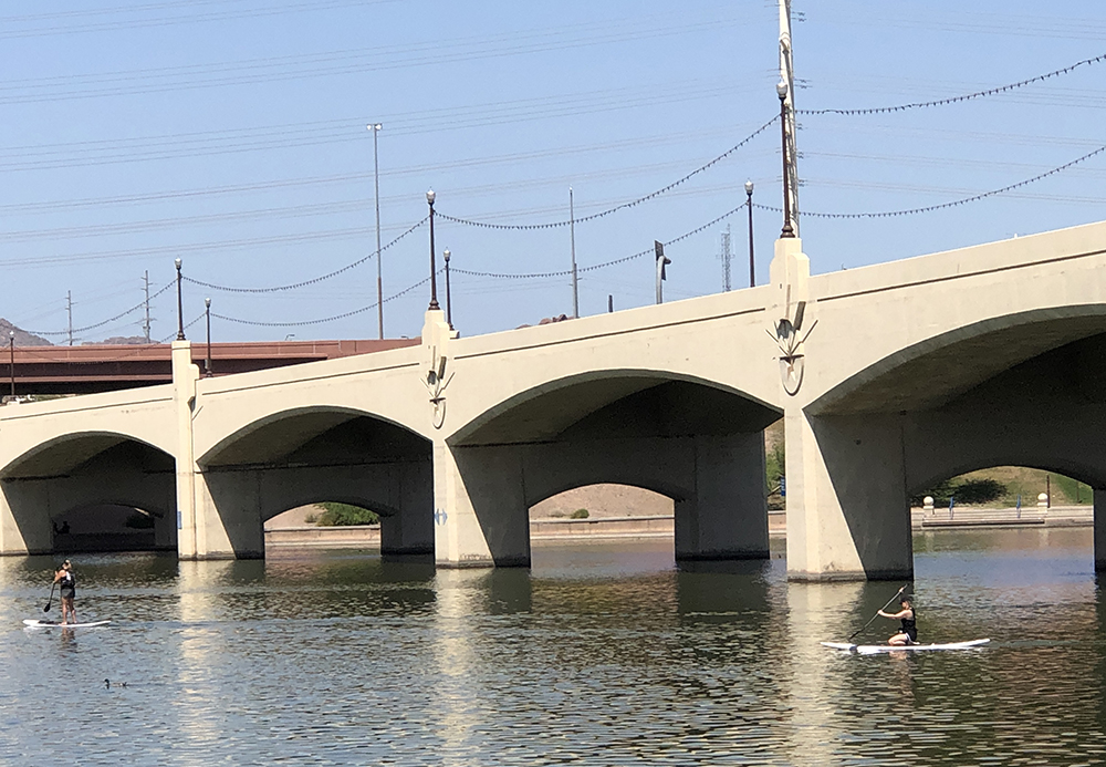 Two people on Tempe Town Lake; one person is kayaking and the other is paddle boarding.